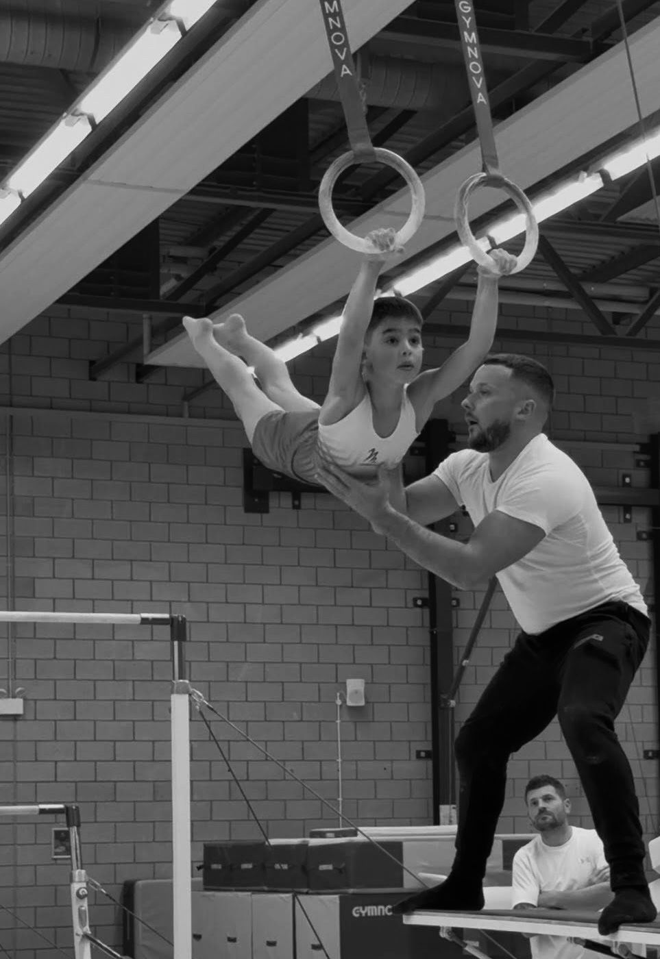 Coach helping gymnast with rings